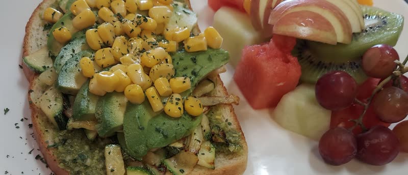 Avocado tartine with corn and zucchini on grilled sourdough