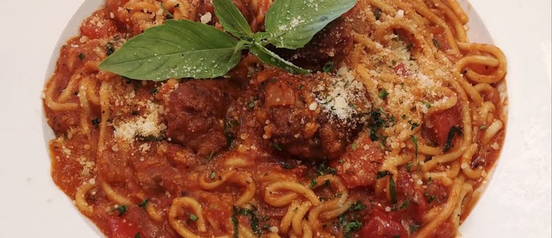 Spaghetti in marinara sauce with meatballs, parmesan and fresh basil